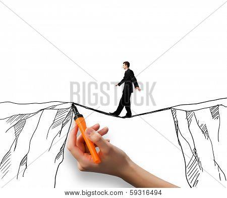 Brave businessman walking on rope above mountain gap