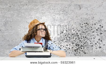 Young funny woman in glasses using typewriter