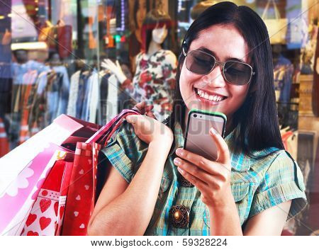 Asian Woman Carrying Shopping Bags And Texting Massage