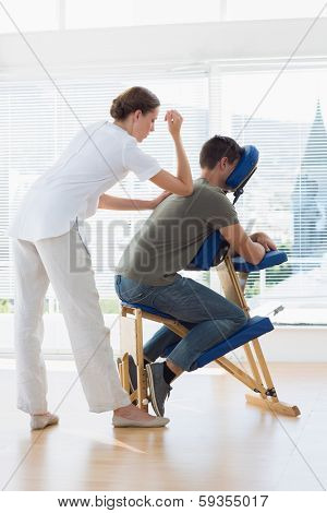 Full length of female therapist giving back massage to man in hospital