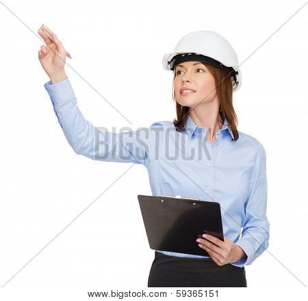 building, developing, consrtuction and architecture concept - smiling businesswoman in white helmet with clipboard pointing finger