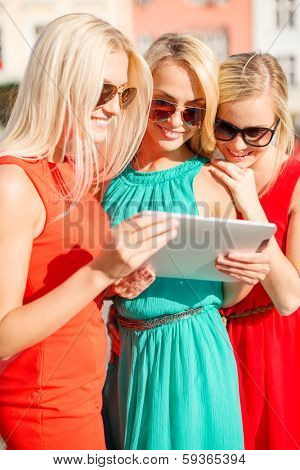 holidays and tourism concept - beautiful blonde girls toursits looking into tablet pc in the city