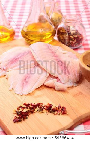 Raw fish tilapia on cutting board and spices