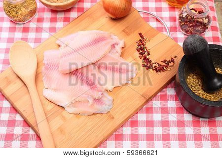 Raw fish tilapia on cutting board and spices