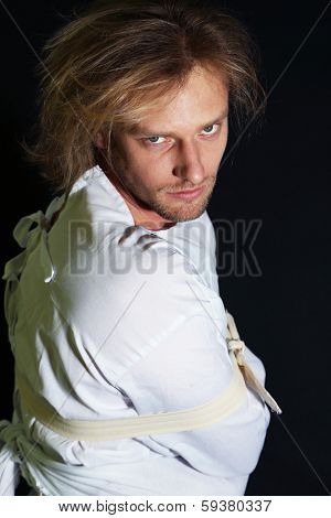 Mentally ill man in strait-jacket on black background