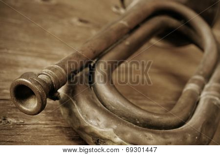 old bugle on a rustic wooden table, in sepia tone