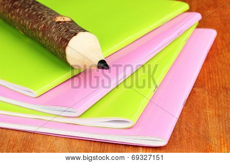 Colorful wooden pencil with exercisebooks on wooden table