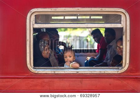 HIKKADUWA, SRI LANKA - MARCH 12, 2014: Local people in train looking through window. Trains are very cheap and poorly maintained but it's the best option to witness a bit of everyday local life.