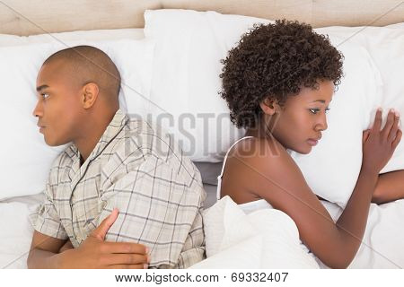 Unhappy couple lying on bed not talking at home in the bedroom