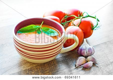 A bowl of tomato soup gaspacho with basil, tomatoes and garlic