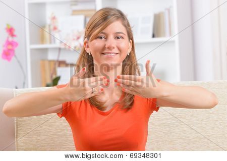 Beautiful smiling deaf woman using sign language or showing OK sign