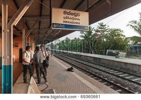 HIKKADUWA, SRI LANKA - FEBRUARY 22, 2014: Commuters wait for train at Hikkaduwa station. Trains are very cheap and poorly maintained but it's the best option to witness a bit of everyday local life.