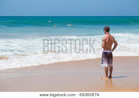 HIKKADUWA, SRI LANKA - FEBRUARY 24, 2014: Surfer checking out waves on the horizon. Hikkaduwa is well known tourist international destination for board surfing.