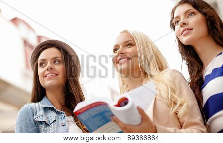 holidays and tourism concept - beautiful girls with city guide book