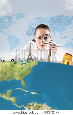 Businesswoman typing and looking through magnifying glass against background with hexagons and world map