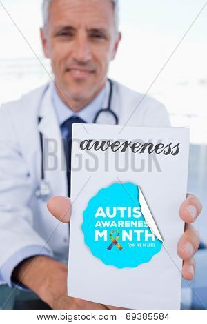 The word awereness and portrait of a male doctor showing a blank prescription sheet against autism awareness month