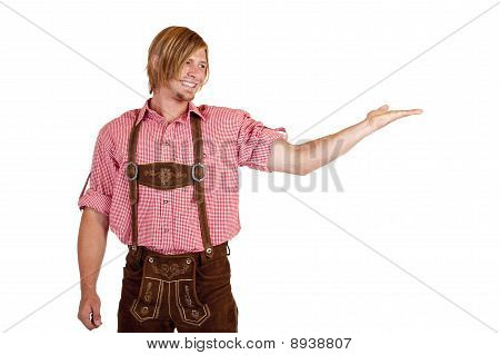 Felice uomo con pantaloni di cuoio oktoberfest (lederhose) tiene la mano aperta per la pubblicità.