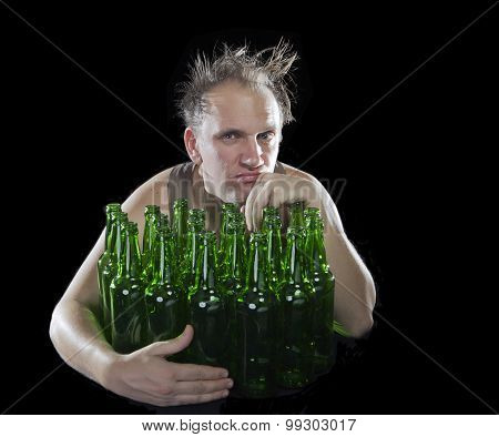 The tipsy man sits with a heap of beer bottles a hangover