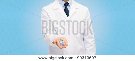 healthcare, profession, people and medicine concept - close up of male doctor in white coat holding sky blue prostate cancer awareness ribbon