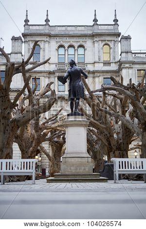 LONDON, UK - SEPTEMBER 23: Statue of Sir Joshua Reynolds amongst Ai Wei Wei's installation 'Tree' in the forecourt of the Royal Academy of Arts. September 23, 2015 in London.