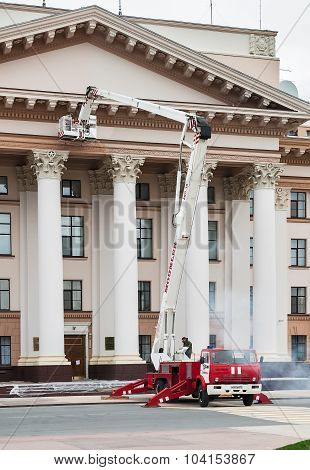 Builders paint building facade by fire truck