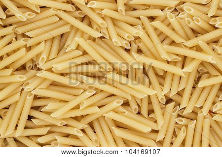 dry uncooked penne lisce pasta texture background