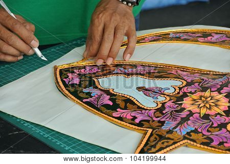 Malaysian kite maker working on a kite in his workshop