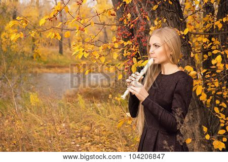 Beautiful Young Blonde Woman Playing Flute Recorder In Autumn Forest