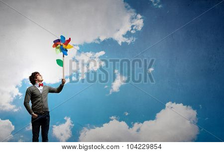 Young happy guy in casual with colorful windmill in hand