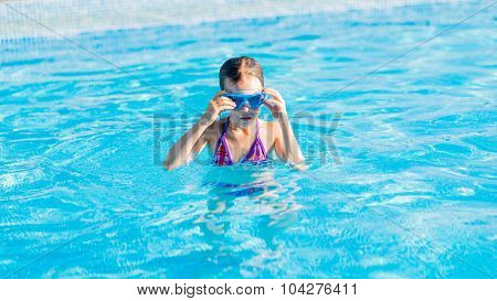 Happy Girl In Blue Goggles Swimming In The Swimming Pool