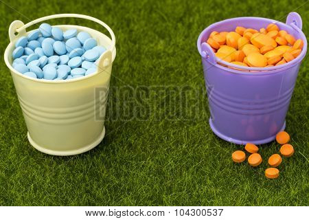 Pharmaceutical concept. Two buckets filled with orange and blue pills
