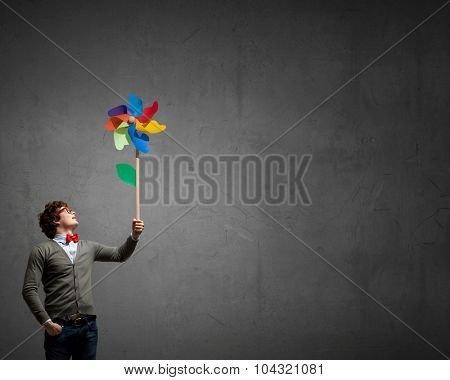 Young happy guy in casual with colorful windmill in hand