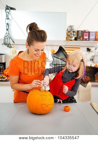 Happy Mother With Daughter Creating Jack-o-lantern On Halloween