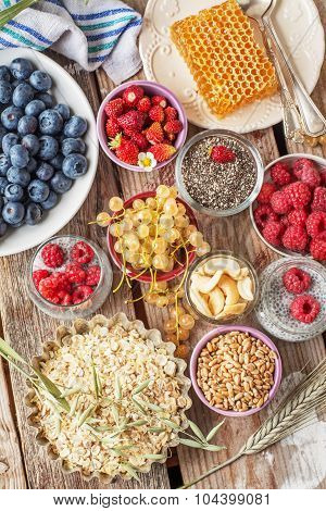 ingredients for a healthy breakfast - berries, fruit and muesli on wooden table, close-up