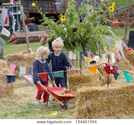 Children Playing With Hay And A Wheel Barrow