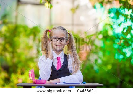 Portrait of happy little school girl in glasses outdoor