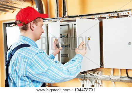 electrician builder engineer inspector checking data of equipment in fuse box