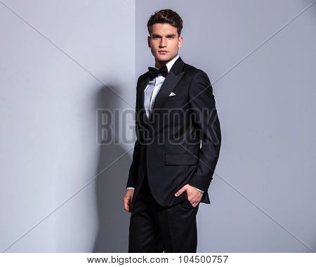 Side view of a young business man looking at the camera while holdinh his hand in pocket.