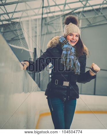 Happy newbie girl on ice skating rink 