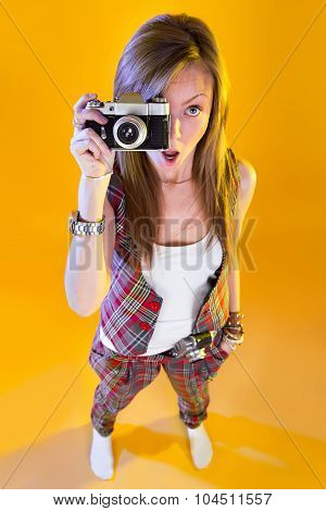 Funny Girl In Full Growth With A Camera In Hand. Surprised By Samer Looking At Viewer. Isolation On