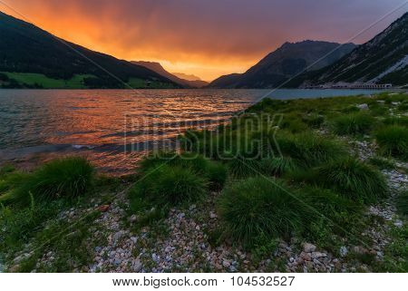 Beautiful view of the lake Resia. Dramatic sky and colorful sunset. Alps, Italy, Europe.