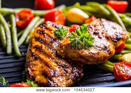 Grilled chicken breast in different variations with cherry tomatoes, green French beans, garlic