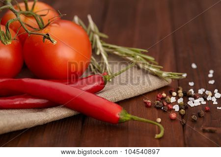 Red chili pepper, salt, tomatto and rosemary on wooden board.
