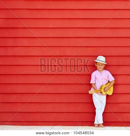 Cute Kid With Ukulele Play Music Near The Colorful Wall