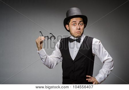 Young man in classical black vest and hat against gray
