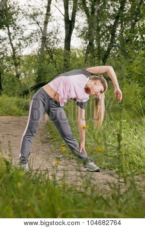 Beautiful Young Blonde Woman Doing Side Bends On A Forest Footpath