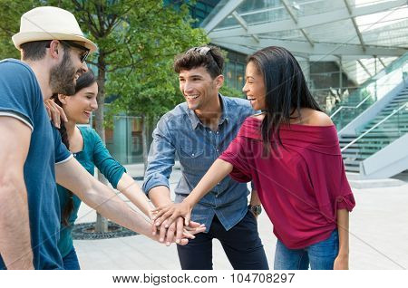 Closeup shot of young friends making huddle with their hand. Happy smiling friends. Happy young friends making huddle. Portrait of a group of people with their hands stacked in a city center.