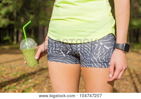 Woman standing  with green smoothie in her hand
