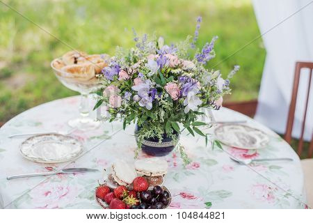 Served table outdoors. Flower arrangement with lavender and roses. Wedding decorations.