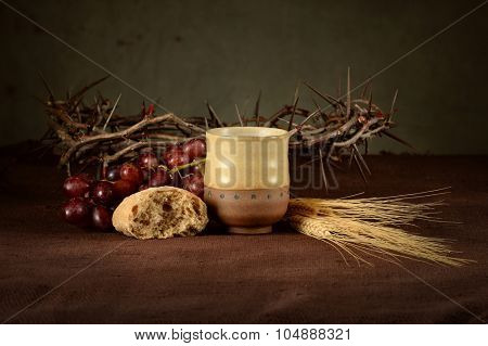 Communion concept with cup of wine, bread, crown of thorns, red grapes and wheat on table